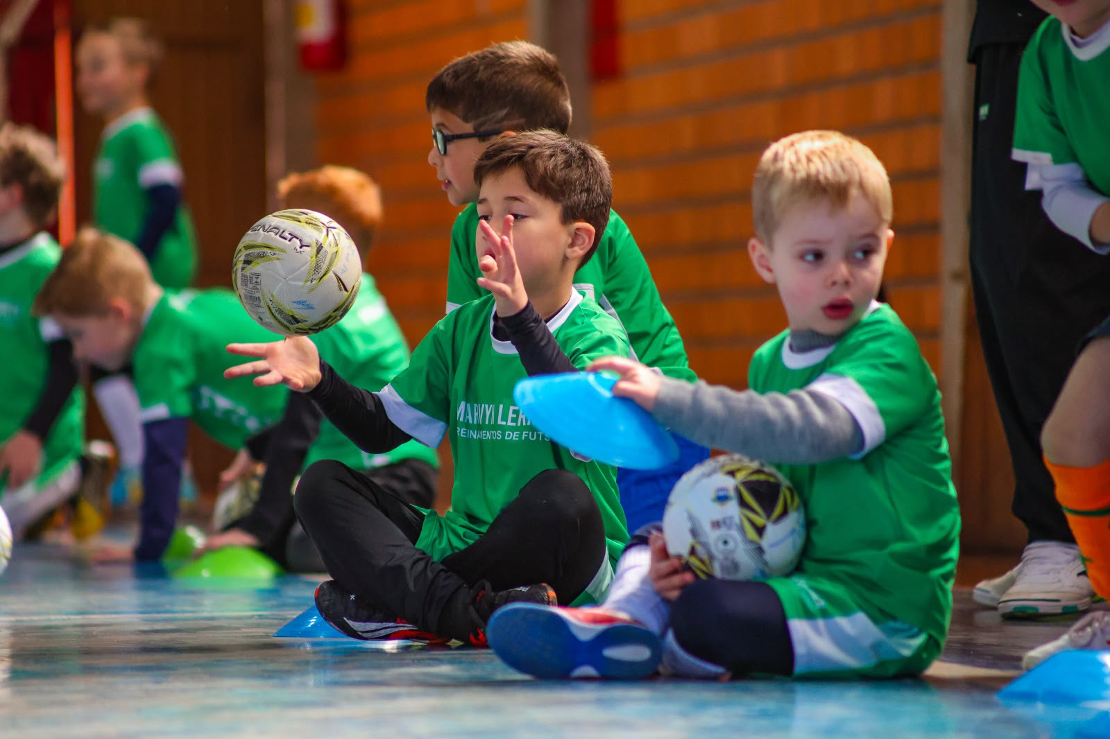 Crianças em treino de futsal com bolas e cones em quadra